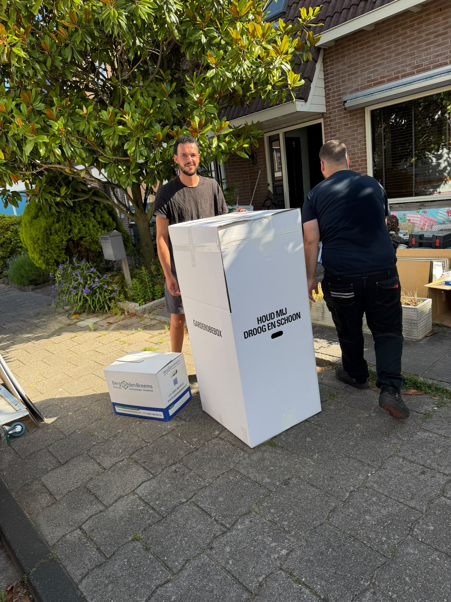 Verhuizers met garderobebox bij een woning