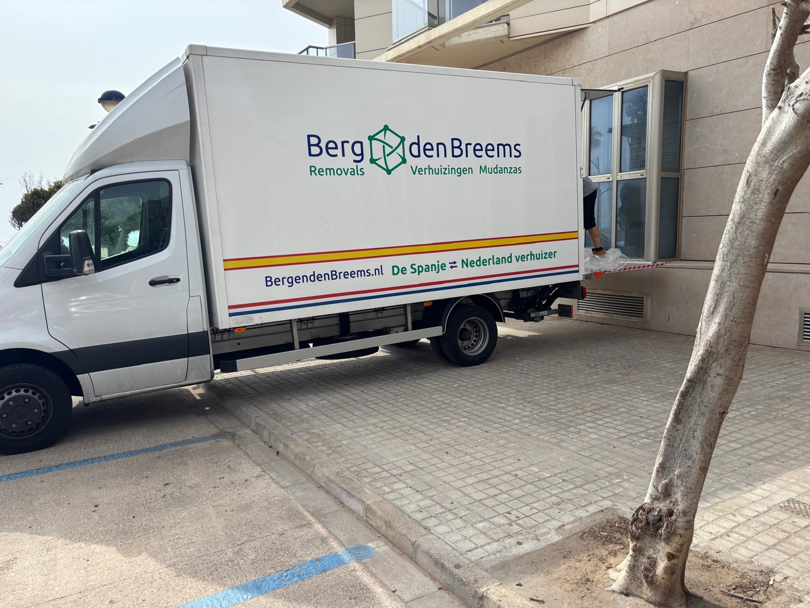 Verhuiswagen van Berg en den Breems lost via het raam bij een woning in Spanje