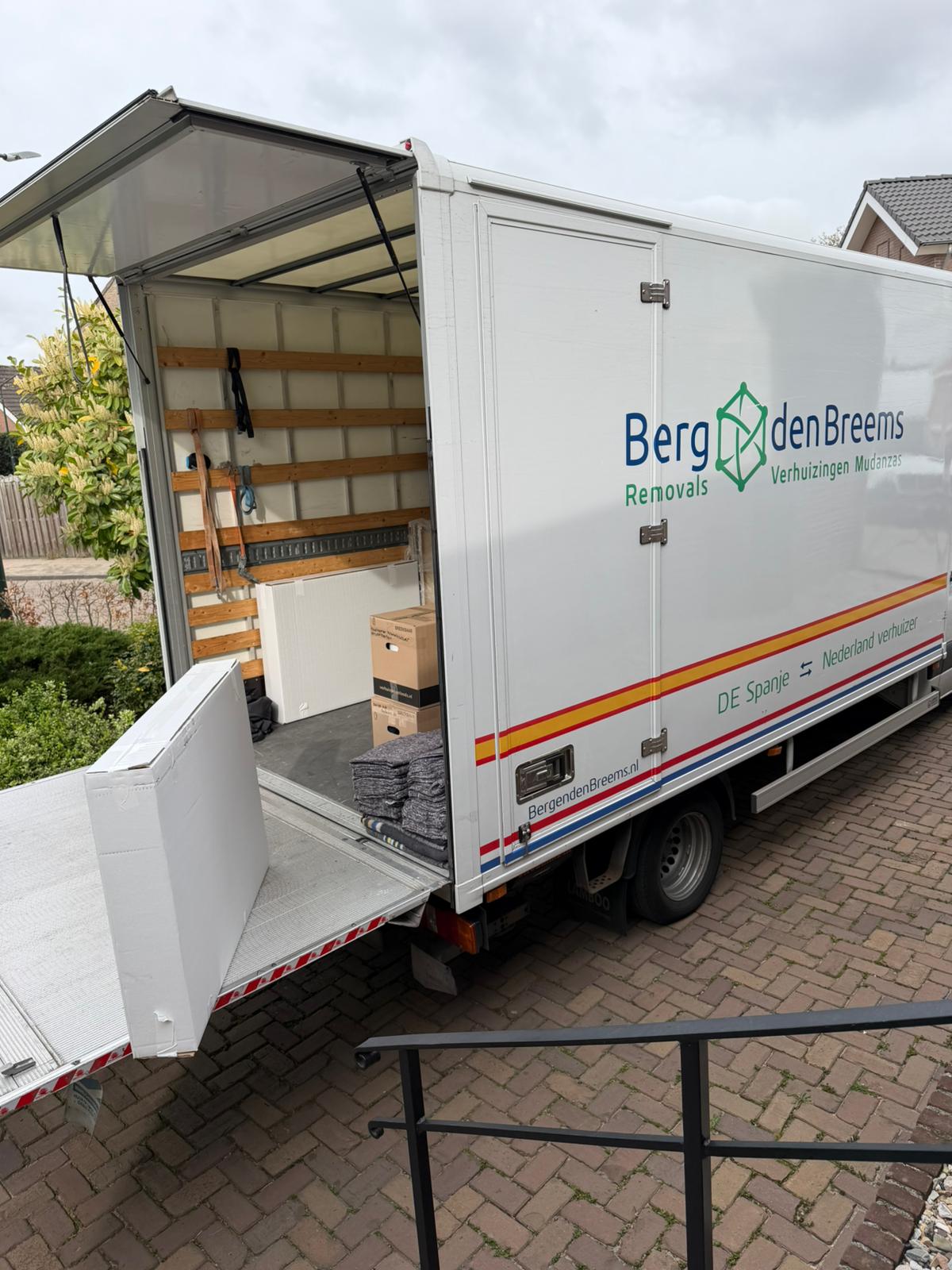 Verhuiswagen van Berg en den Breems op de oprit bij een woning